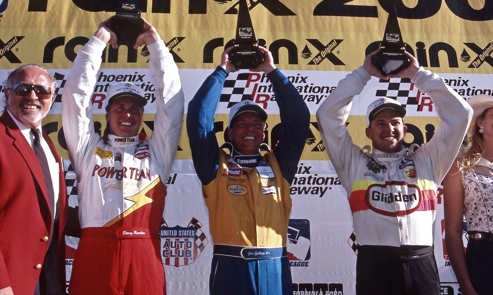 Jim Guthrie holding the winner's trophy on the Phoenix 200 podium in 1997, flanked by Davey Hamilton and Tony Stewart