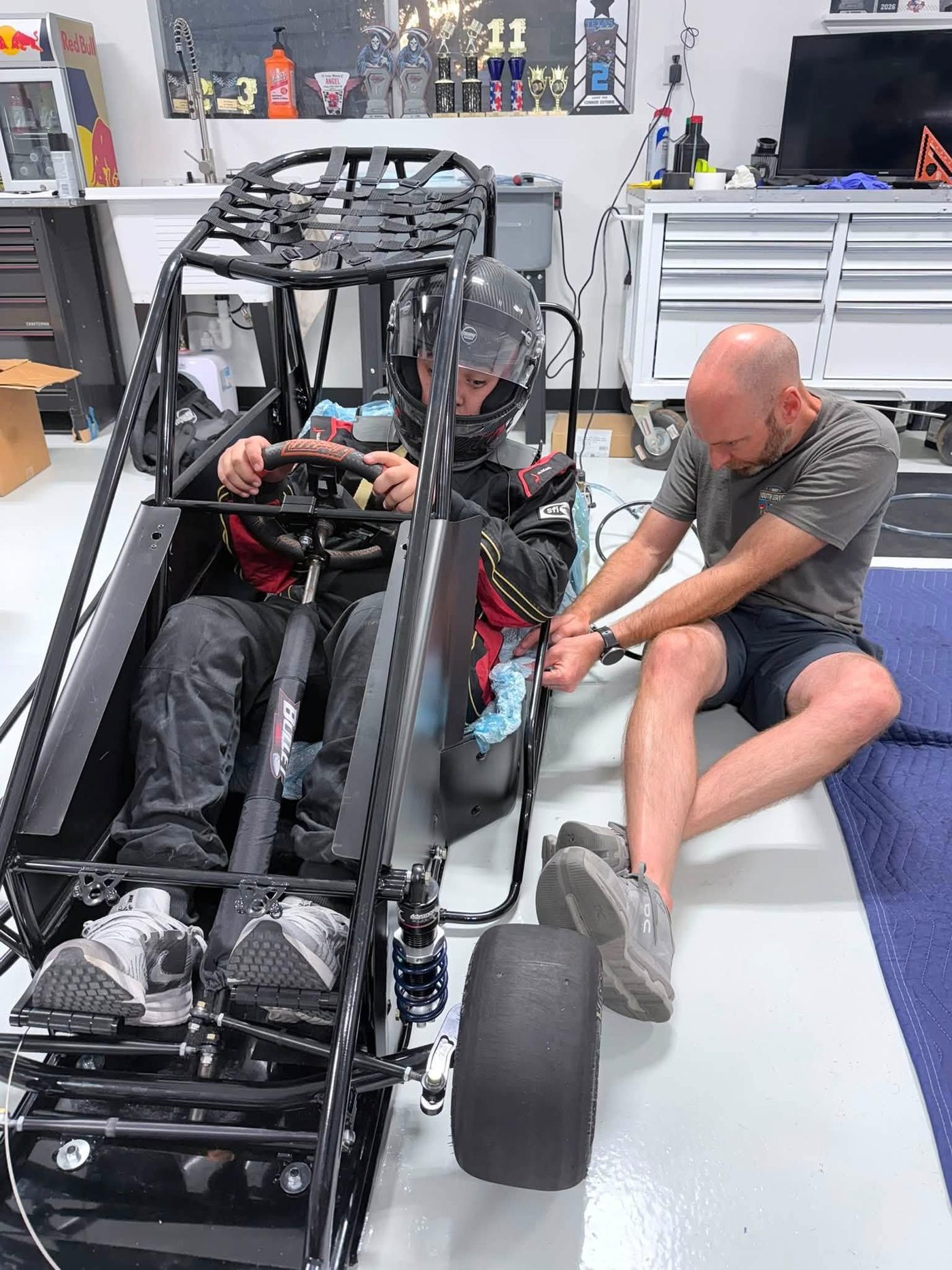 A driver seated in a quarter midget while the seat is fitted